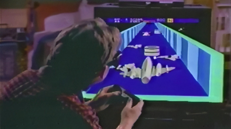 A person playing an early 3D video game on a CRT television using a joystick controller.
