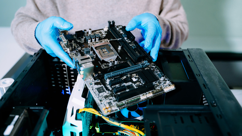 Person installing a motherboard into a desktop PC case during a computer build.