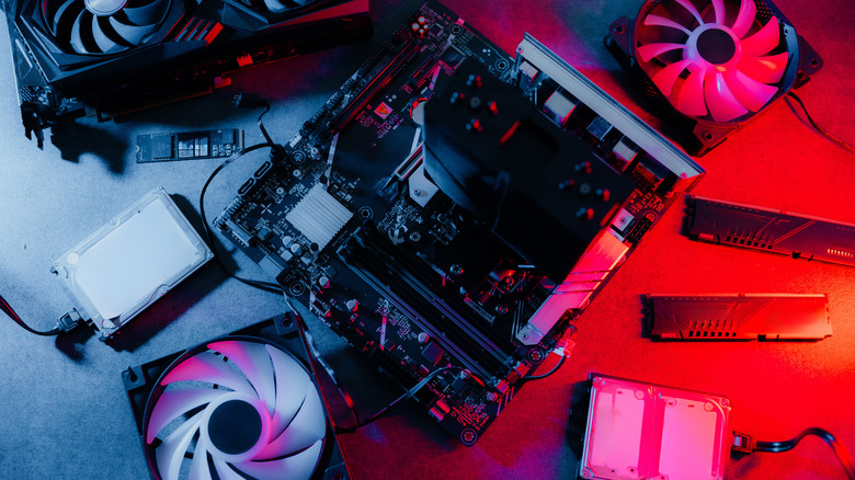 Pile of desktop PC components including a power supply, graphics card, storage drives, RAM, keyboard, and mouse.