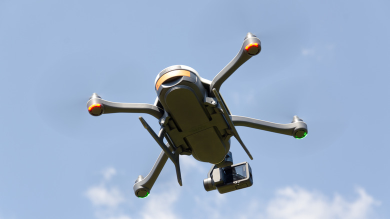 A camera-equipped quadcopter drone flying against a blue sky.
