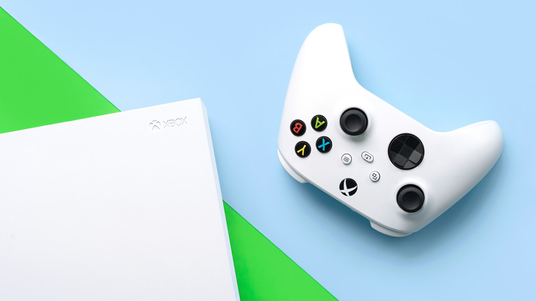 A white Xbox console and wireless controller on a blue and green background.