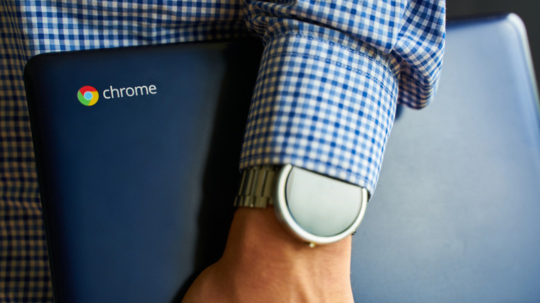 A man holding a Chromebook with a sticker of the Chrome logo and label
