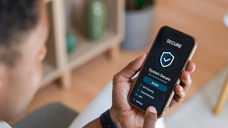 A person looking at their phone as it shows a screen saying that the system is secure