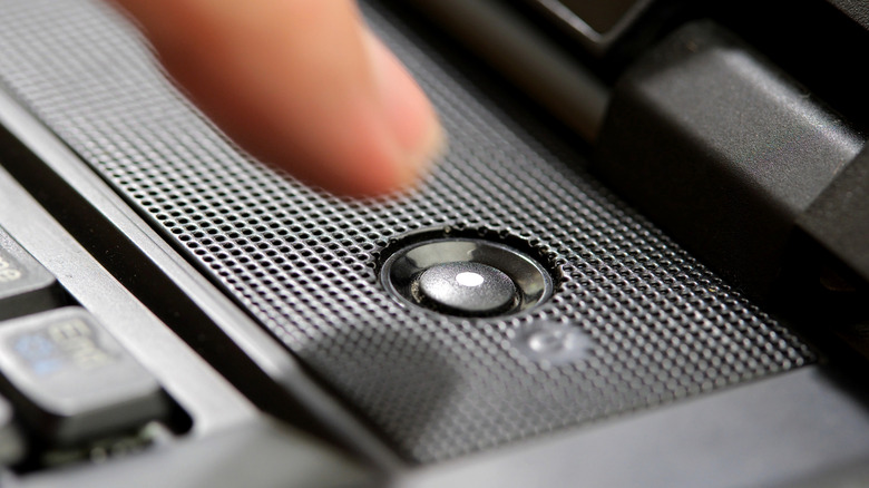Zoomed-in view of a person pressing the power button on a laptop