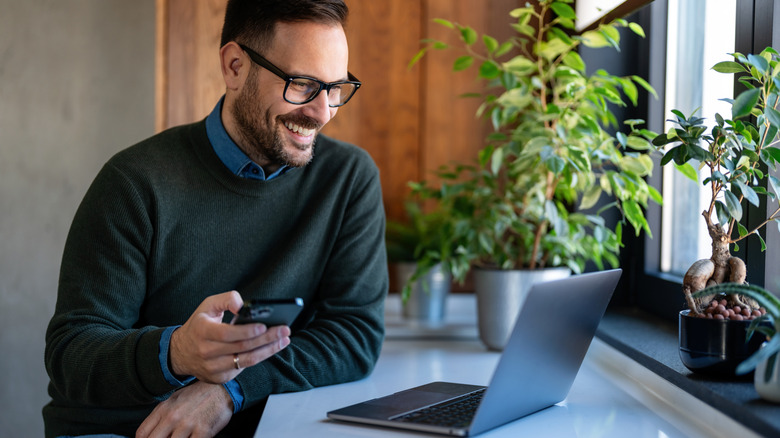 A man smiling while looking at his laptop