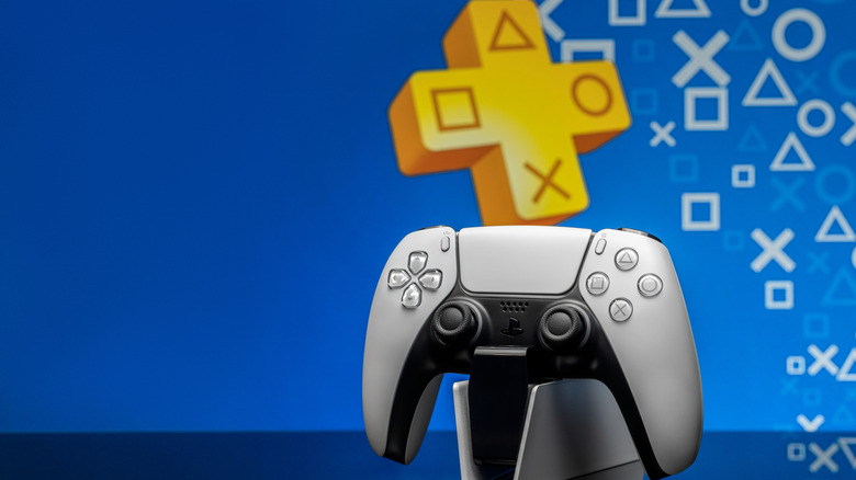 The PlayStation 5 controller on a charging stand, with the PlayStation Plus logo in the background.