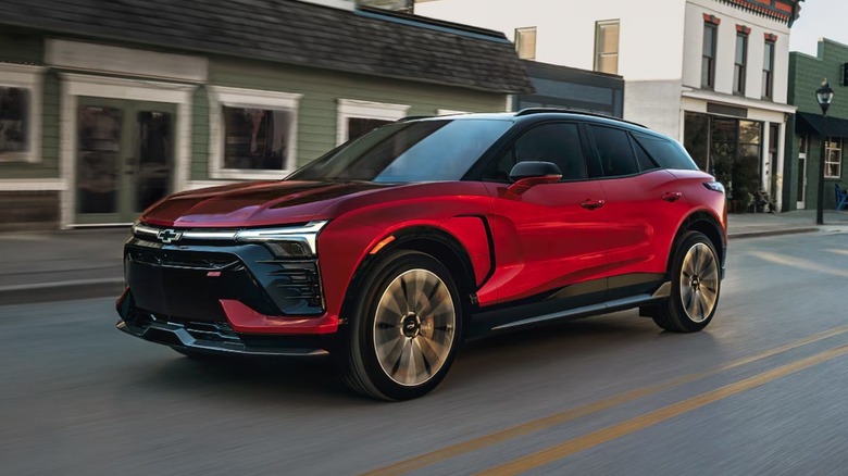 A red Chevrolet Blazer EV driving down a street with short buildings in the background