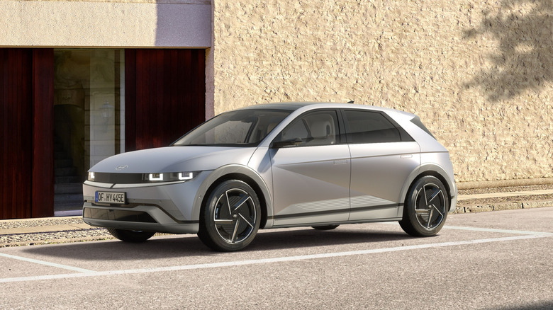 A silver Hyundai Ioniq 5 parked in front of a sand-colored building