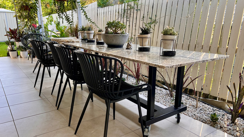 A fancy outdoor patio dining area, with a table, chairs, and potted plants