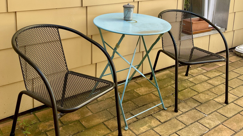 A pair of metal outdoor chairs around a table in a little backyard area