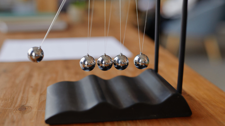 A Newton's cradle desk toy in action on a desk.