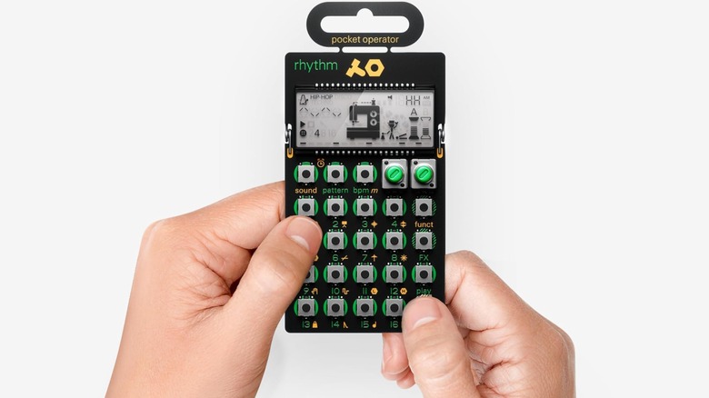 Two hands operate a Teenage Engineering PO-12 Rhythm Pocket Operator against a white background.