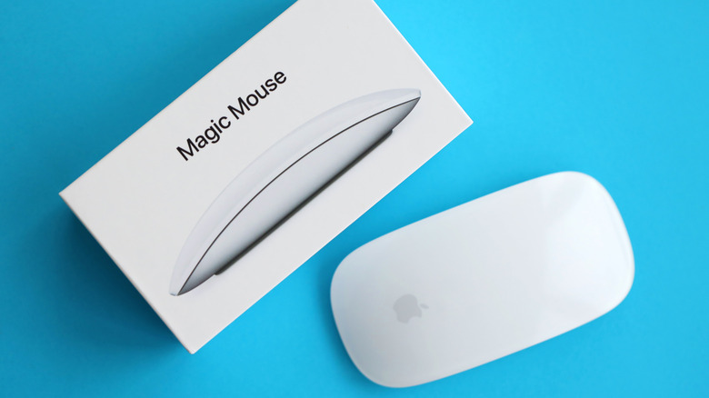 A white Magic Mouse with its packaging on a blue backdrop.