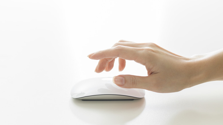 A hand hovering over a Magic Mouse on a white background.