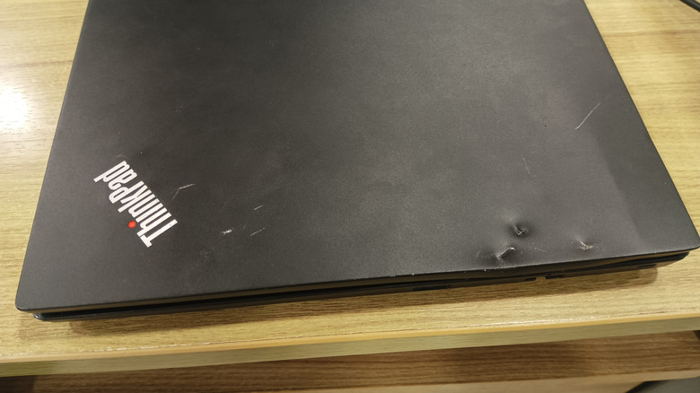 A closed Lenovo ThinkPad with visible impact dents on the lid.