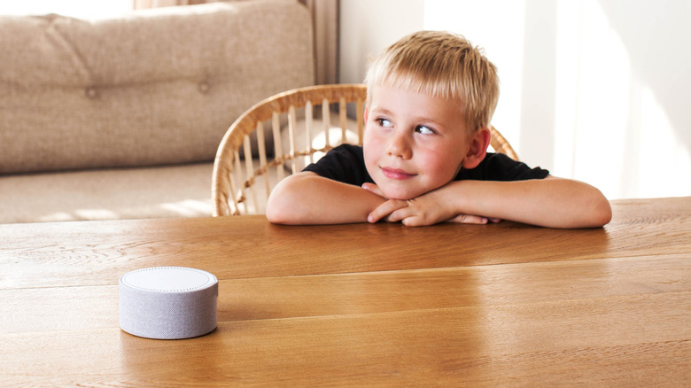 Child sitting at a table and talking to a smart speaker