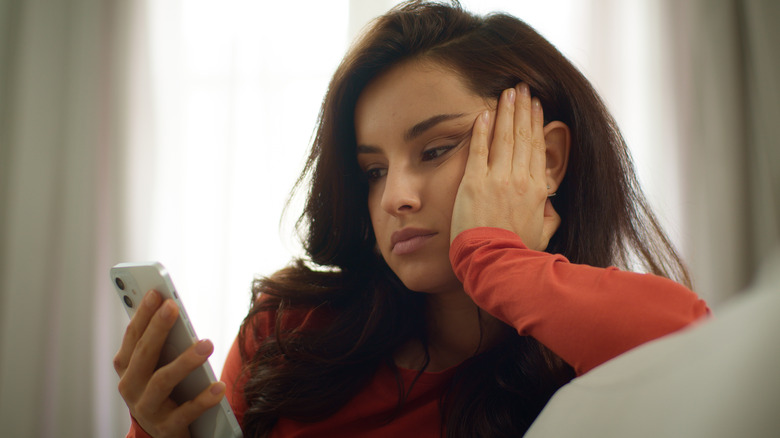 Woman looking bored as she stares at her phone