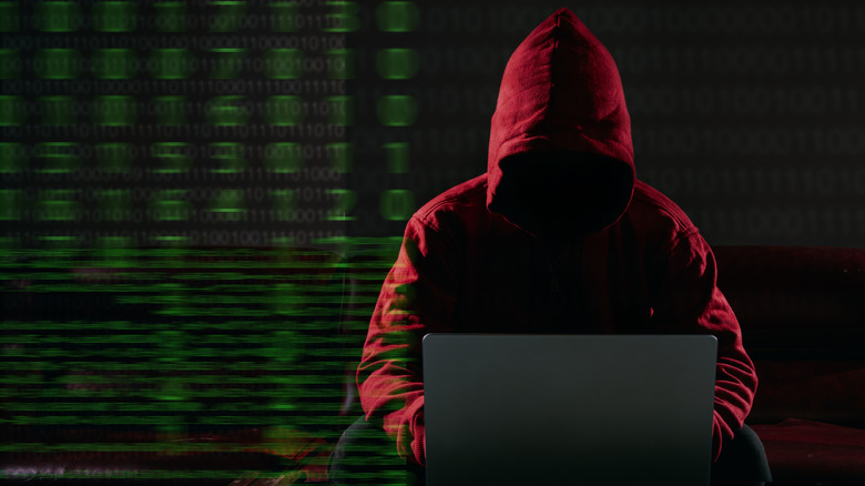 Hacker in hoodie working on a laptop