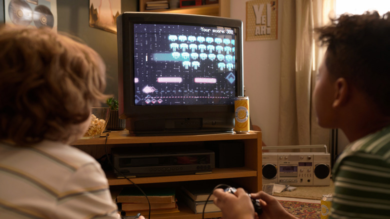 Two kids playing a retro game on a CRT monitor.