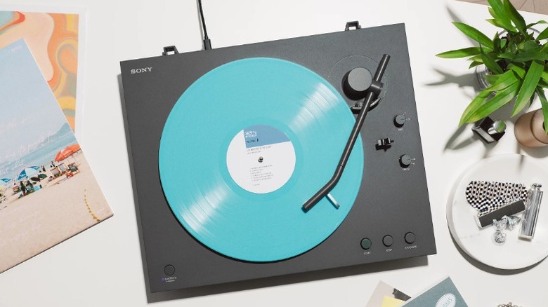 The Sony PS-LX3BT Bluetooth Turntable on a table next to a plant and other decor.