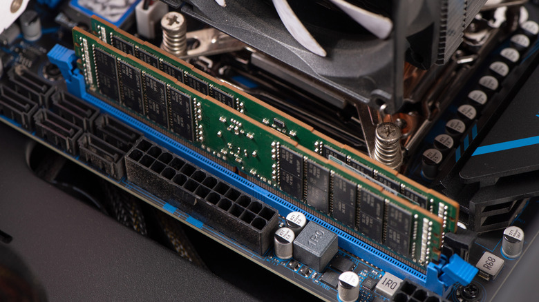 A close-up of a desktop computer motherboard showing installed DDR RAM sticks next to a CPU cooler and the motherboard's 24-pin power connector.