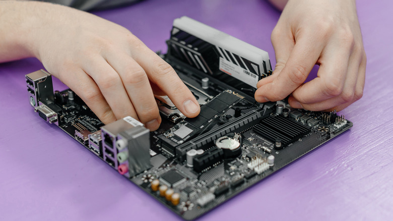 Person installing SSD and RAM in computer motherboard