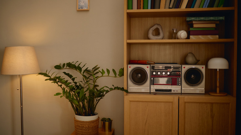 A vintage boombox casette player on a bookshelf.