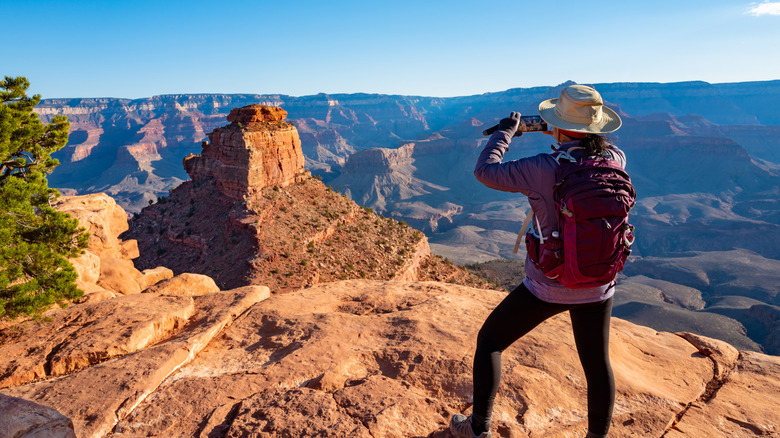 A person films from the top of the Grand Canyon.