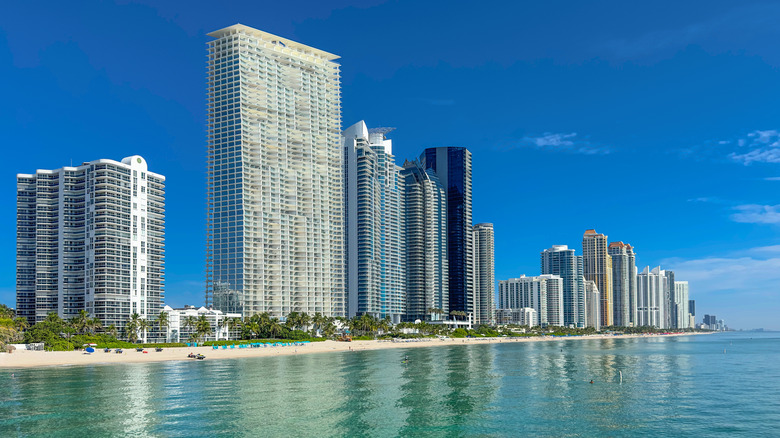 Several tall buildings stand next to the beachfront.
