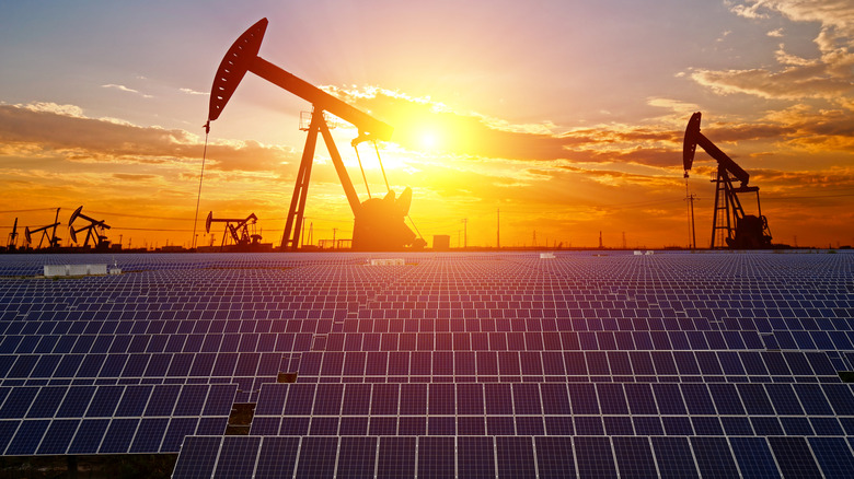 Solar panels in Texas with oil pumps and a sunset in the background