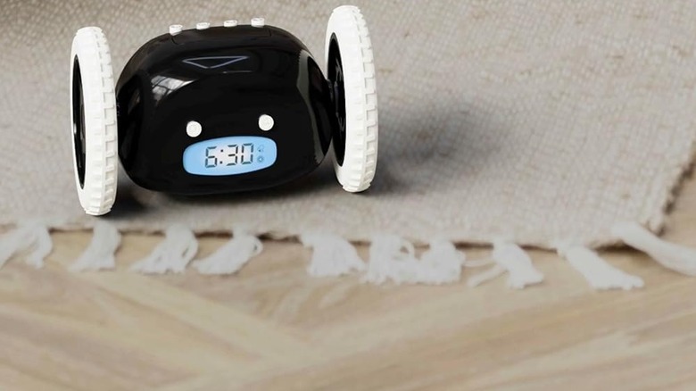 The Clocky alarm clock robot on a carpet placed on a wooden floor