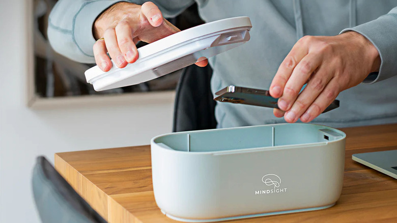 A person placing a phone inside the Mindsight Timed Lock Box