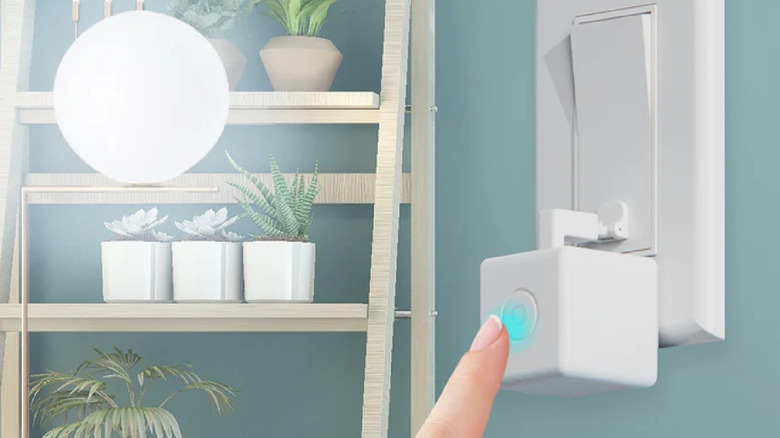 A person pressing the button on the MOES Fingerbot Plus