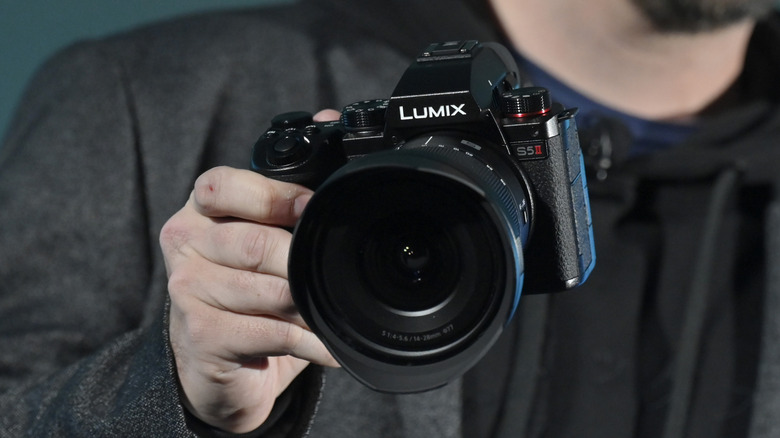 A hand holding a Panasonic Lumix S5II camera.