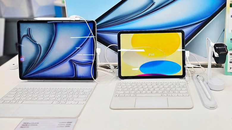 Two iPads, and an Apple Watch, on a store display shelf.