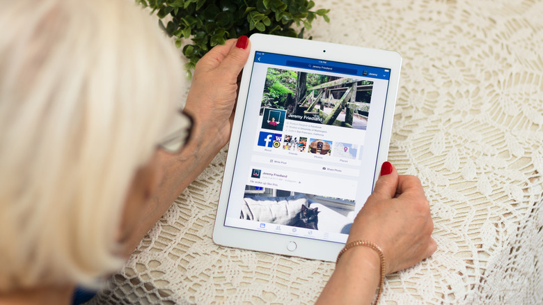 A person looking at an older-model iPad, still bearing the touch button.