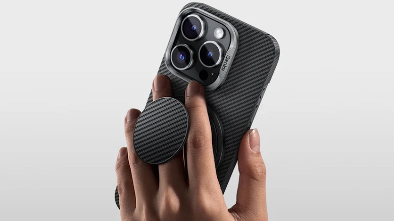 A person holding up an iPhone with the Benks Armor Magnetic Grip attached to the back