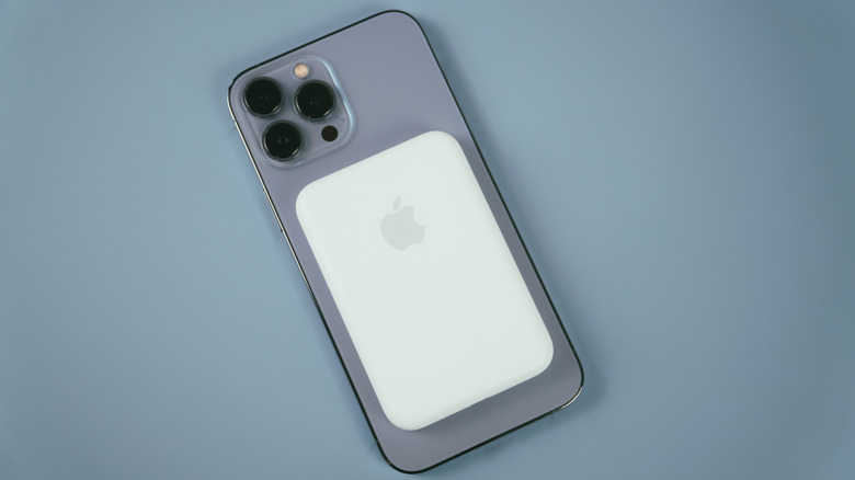 An iPhone 13 Pro in Sierra Blue with an Apple MagSafe Battery attached to it.