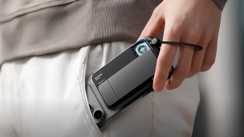 A person putting an iPhone 17 Pro in their pocket with the Sharge Icemag 3 MagSafe Power Bank attached to the back of it.