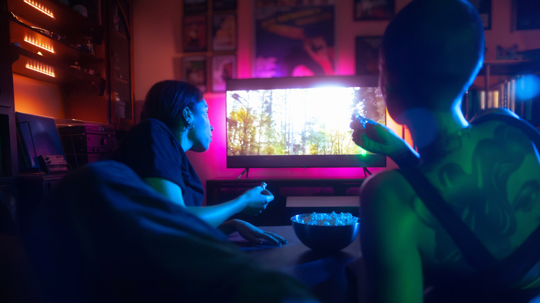 Two young women watching film at night and eating popcorn.