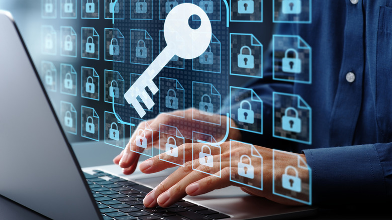 A laptop with a graphic of padlocks and a key hovering above it as a person types.