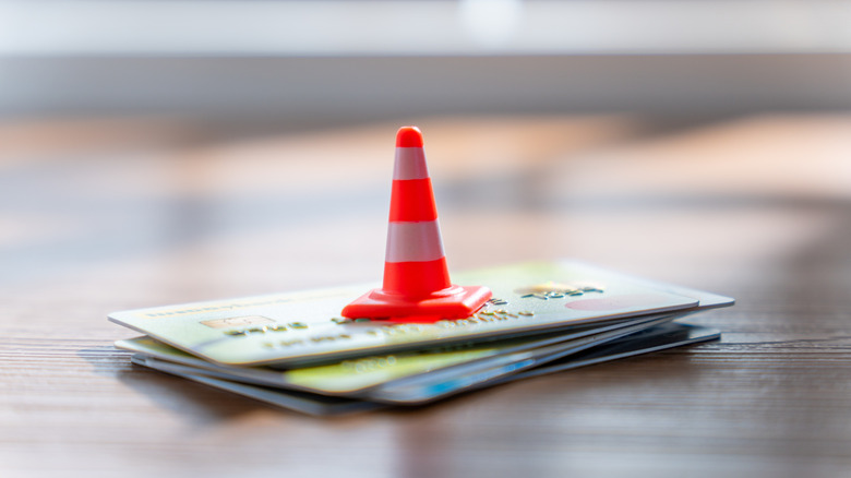 A stack of credit cards with a traffic cone on top.