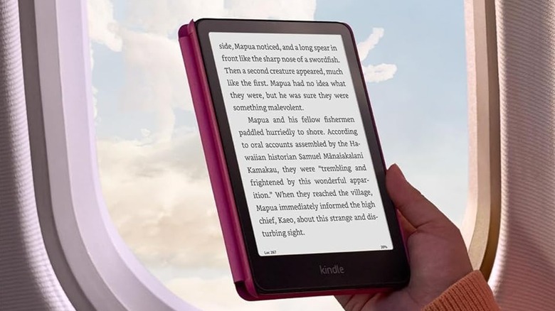 A person reading on an Amazon Kindle Paperwhite ebook reader while in an airplane.