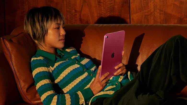 A person using the Apple iPad (A16) tablet on a couch.