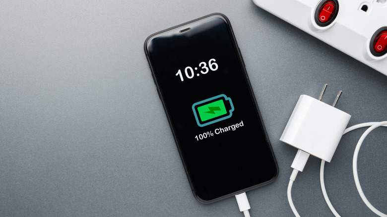 A phone with a 100%-charged battery status icon on the screen.