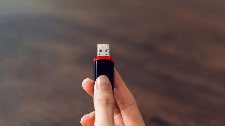 A hand holding a USB flash drive