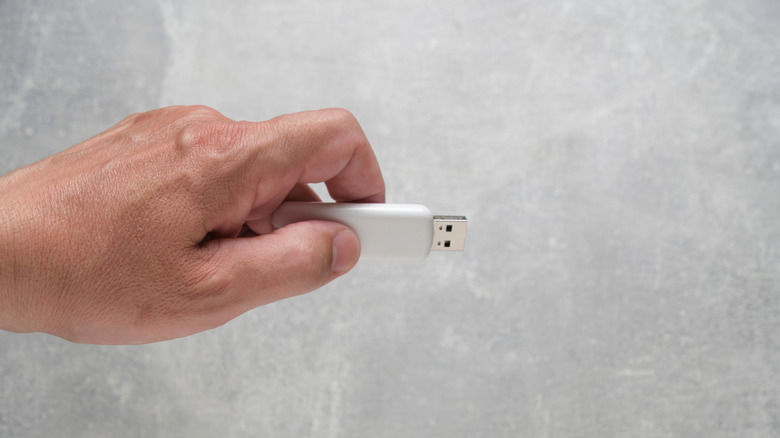 A hand holding a USB flash drive