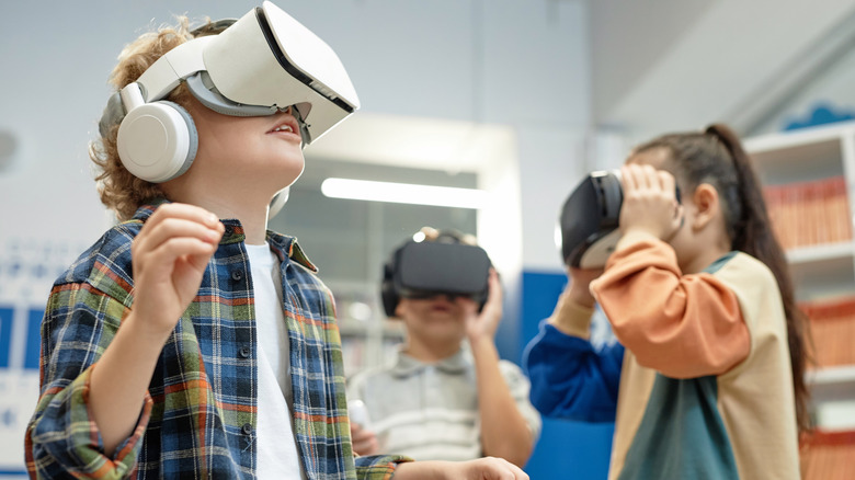 Children wearing virtual reality headsets and exploring VR experiences together in a classroom or learning environment.