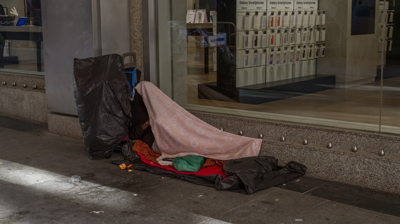 a homeless person under a blanket on the street