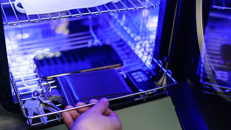 A smartphone and other items being sanitized in a UV tray